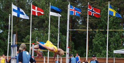 Marcus Nilsson, Högby IF, hoppar höjd med Nordiska flaggor i bakgrunden. Foto: Calle Nilsson.